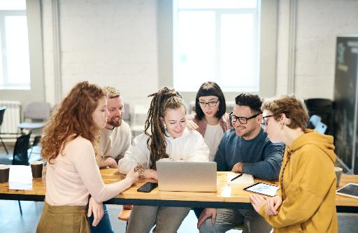Grupa studentów pracująca wspólnie przy jednym laptopie 