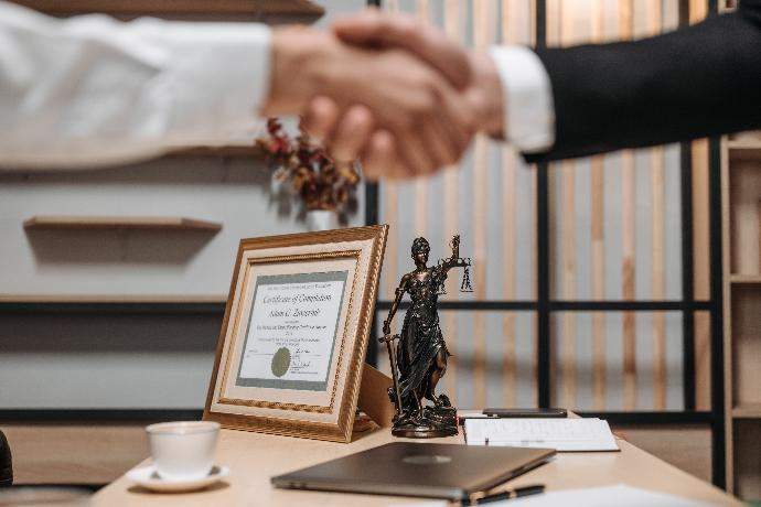 Dwie ręce zgadzające się nad posągiem symbolizującym sprawiedliwość