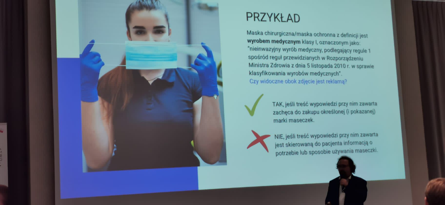 Zdjęcie przedstawiającego mężczyznę wygłaszającego wykład, w tle prezentacja