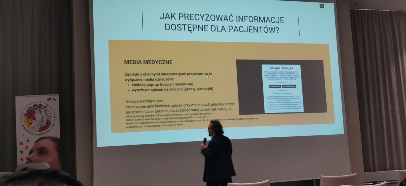 Zdjęcie przedstawiającego mężczyznę wygłaszającego wykład, w tle prezentacja